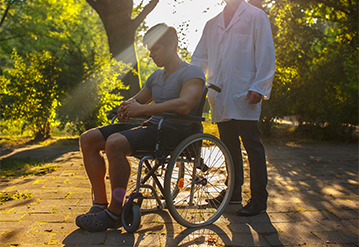 Young men in wheelchair taking a walk with his caregiver 